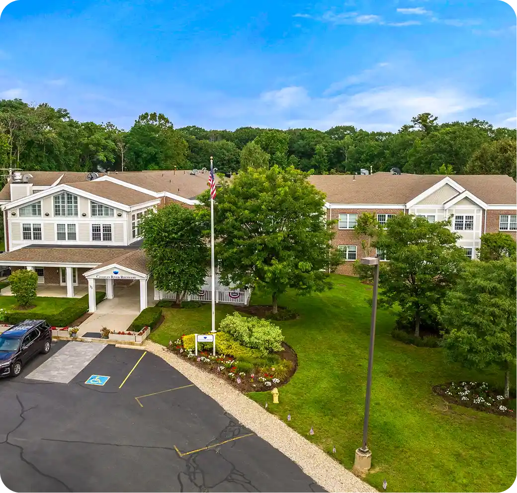 Charles River Recovery facility exterior, featuring landscaped grounds, flagpole, and parking area, highlighting a supportive environment for addiction treatment services.