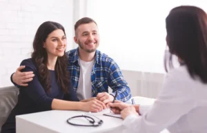 Couple meeting with healthcare professional discussing financial assistance for addiction treatment in Massachusetts.